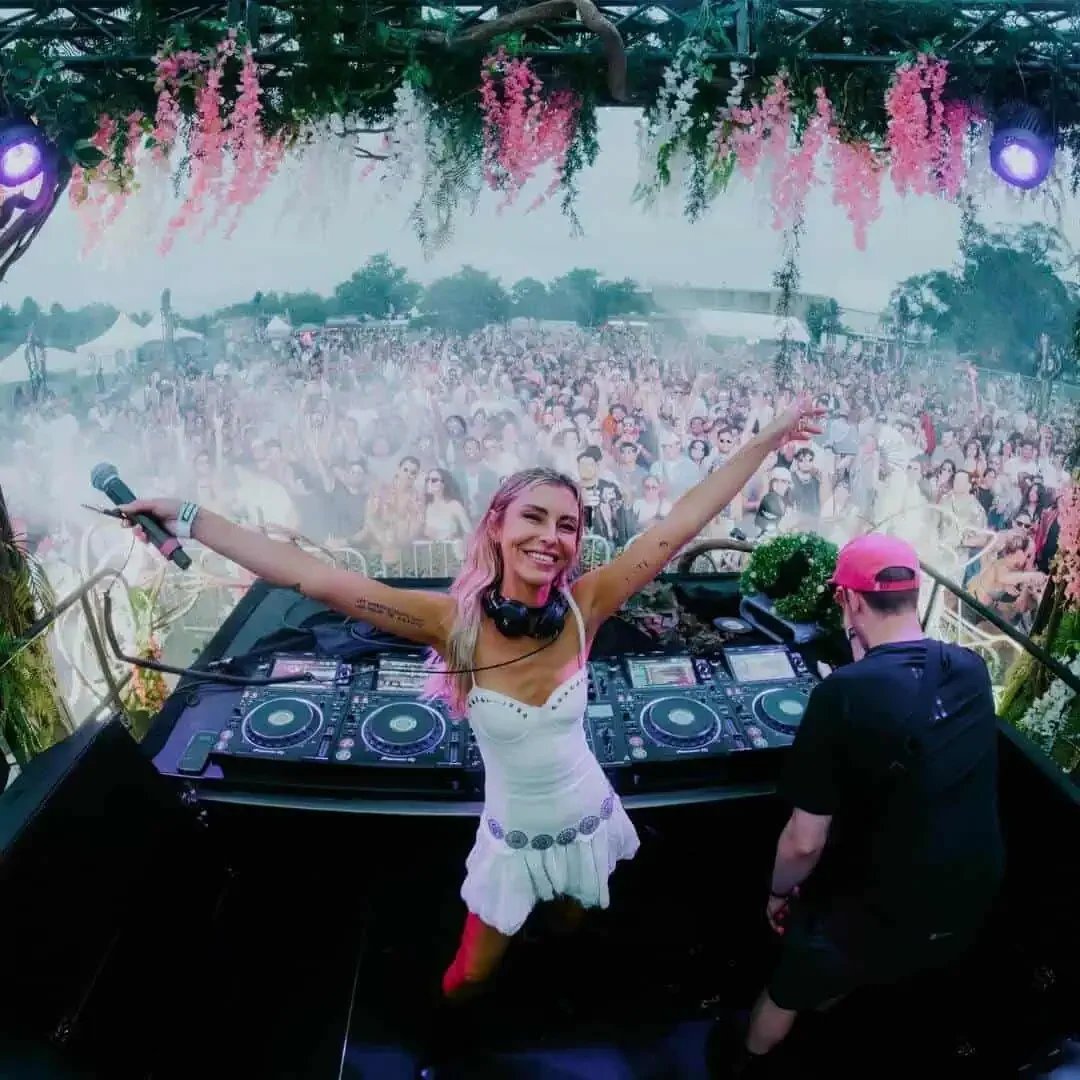 Sam Blacky performing live on festival mainstage — arms raised, crowd of thousands behind her